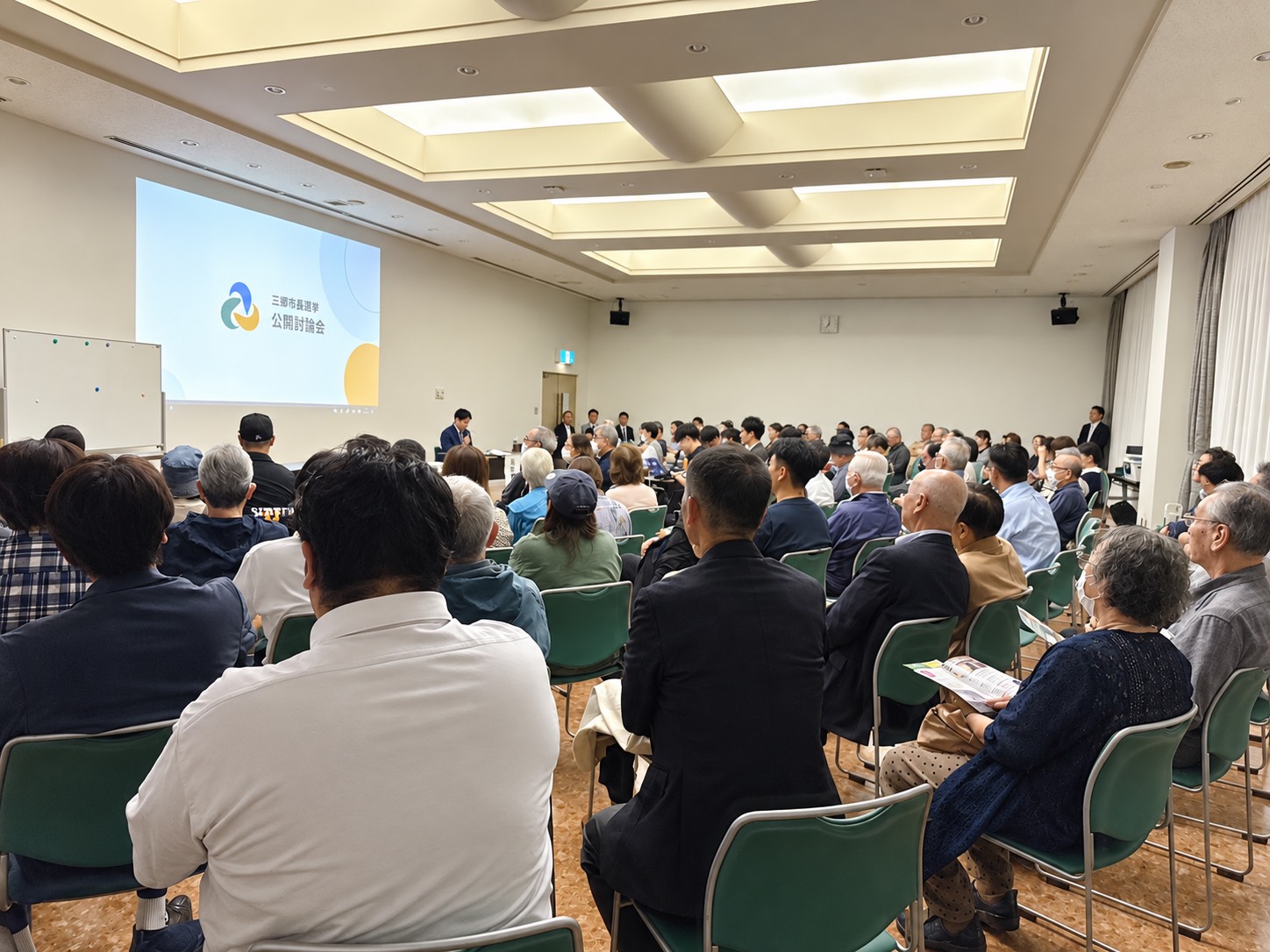 10月14日、三郷市文化会館大会議室で公開討論会に参加する来場者